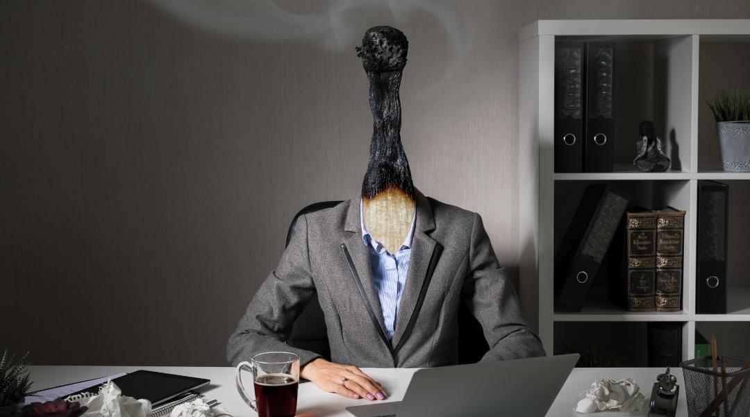 Person at desk in suit but face and head are a burned out matchstick